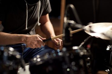 music, people, musical instruments and entertainment concept - male musician playing drums and cymbals at concert or studio